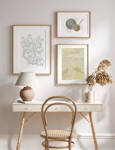 a white desk topped with a lamp next to pictures