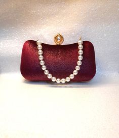 Add a touch of elegance to your evening ensembles with this beautiful Wine Red Burgundy Velvet Clutch Bag. Crafted from luxurious velvet in a deep wine red burgundy shade, this clutch radiates sophistication and style. The bag features a unique pearl handle, adding a glamorous and feminine touch. The spacious interior is perfect for holding your essentials, while the magnetic closure keeps your belongings secure. Whether you're attending a formal event or a night out on the town, this velvet clutch is sure to make a statement. Elevate your outfit with this stunning accessory and be prepared to turn heads wherever you go. Size: 20x11x5cm Colour: wine red (burgundy) Luxury Red Wedding Clutch, Luxury Burgundy Clutch For Evening, Traditional Red Luxury Clutch, Luxury Red Classic Clutch, High-end Red Evening Bag, Velvet Clutch Bag, Velvet Clutch, Wedding Purse, Wedding Bags