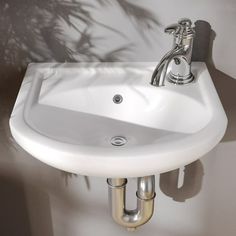 a white sink sitting on top of a counter next to a wall mounted faucet