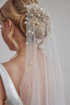 the back of a bride's veil with pearls and beads on her head is shown