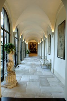 the hallway is lined with arched windows and white marble statues on either side of the walkway