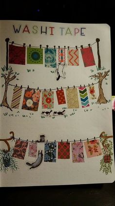 an open notebook with washi tape hanging from it's sides and clothes on the line