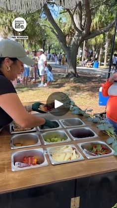 two women are serving themselves food at an outdoor picnic table in the park on a sunny day