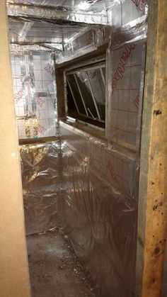 an unfinished room with plastic wrapped around the window and insulation on the wall behind it