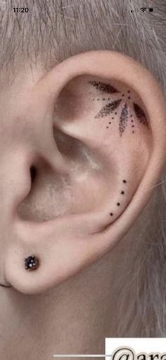 an ear with black dots on it and a small flower tattoo behind the left ear