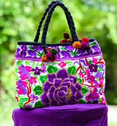 "Hmong Handbag, Womens Purse, Embroidered Bag, Hill Tribe Bag, Colorful Boho Purse, Tapestry Purse, Evening Bag, Flower bag, Red Bag This beautiful bright Hmong multi colored purse / handbag is made from embroidered Hmong fabric in stunning colors. The Hmong are a hill tribe people who live in the north of Thailand - also known as the Lanna region. The bag has a zipper closure at the top and is tapered from the top to the bottom -   which adds a nice shape to the bag. Inside the bag is lined with a black strong cotton fabric. The is a zipper pocket on the inside for keys, coins etc.  The straps are strong plaited cotton stands, decorated with 4 sets of funky mini pompoms!   A bold and bright choice  for those who are not scared to express there colorful inner self. Each bag is handmade and Multicolor Embroidered Tote Bag For Daily Use, Multicolor Embroidered Tote Bag, Top Handle Bags With Floral Embroidery For Everyday, Everyday Top Handle Bag With Floral Embroidery, Multicolor Embroidery Shoulder Bag For Daily Use, Everyday Handheld Bag With Floral Embroidery, Traditional Purple Rectangular Bag, Handheld Bags With Floral Embroidery For Everyday Use, Floral Embroidery Top Handle Bag For Everyday Use