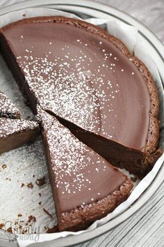 there is a chocolate pie with one slice cut out and powdered sugar on top