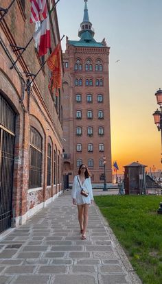 a woman walking down a sidewalk next to tall buildings