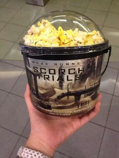 someone holding up a bucket of popcorn at an airport with the caption's name on it