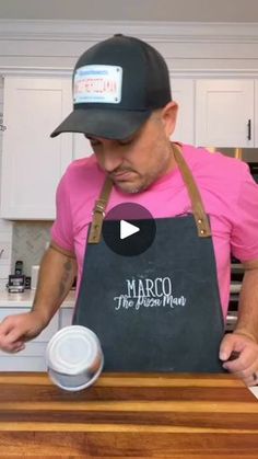 a man in a pink shirt and black hat is preparing food on a cutting board