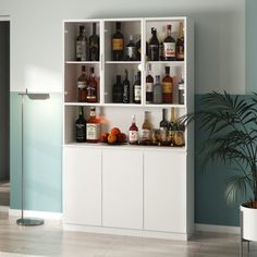 a white cabinet with liquor bottles on it and a potted plant in the corner