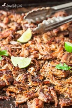 a close up of food on a pan with limes and meat in the background