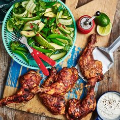 two pieces of chicken on a cutting board next to a bowl of salad and spoons