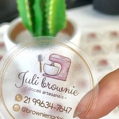 a person holding up a round business card with a logo on it and a cactus in the background