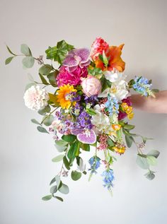 a bouquet of flowers is being held by someone's hand on a white background