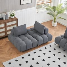 two gray couches sitting on top of a wooden floor next to a white rug