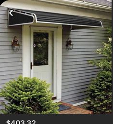 a gray house with a red awning on the front door