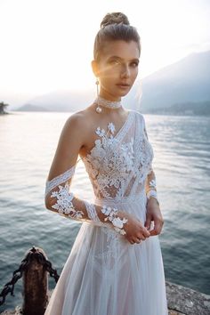 a woman in a white dress standing by the water