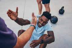 a man sitting on the ground with his hands in the air and two other men standing around him