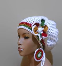 a crocheted white hat with flowers on the side and tassels around the brim