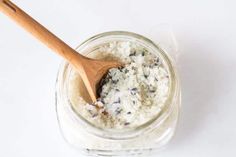 a wooden spoon in a jar filled with white bath salts and lavender florets