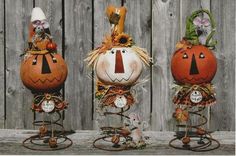 three pumpkins with faces on them are sitting in front of a wooden fence,