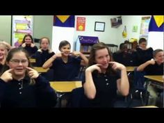 a group of children sitting at desks with their arms around each other's shoulders