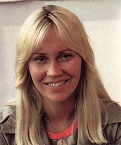 a woman with long blonde hair smiling at the camera