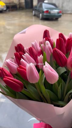 a bouquet of red and pink tulips sitting on top of a table next to a parking lot