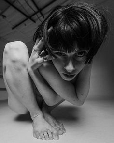 black and white photograph of a woman sitting on the floor with her hands behind her head