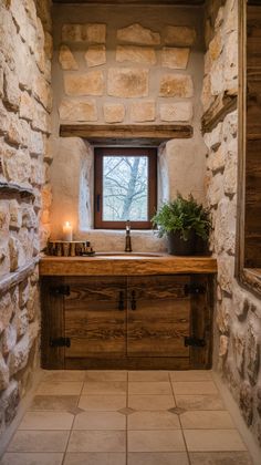 a kitchen with stone walls and flooring next to a window filled with light candles