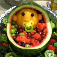 a baby in a watermelon with fruit around it