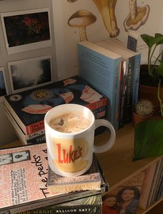 a cup of coffee sitting on top of a stack of books