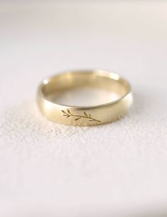 a gold wedding band with the word love engraved on it, sitting on a white surface