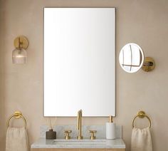 a bathroom with a sink, mirror and gold faucet