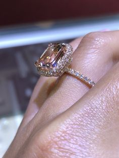 a woman's hand holding an engagement ring with a large pink diamond in it