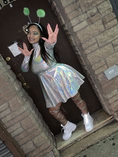 a woman in silver dress standing on steps with her hands up to the camera and smiling