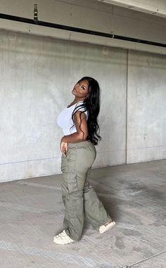 a woman in white shirt and khaki pants standing next to wall with concrete floor