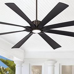 a ceiling fan with four black blades hanging from it's center point in a living room