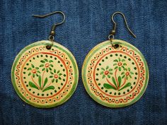 pair of earrings with painted flowers on them sitting on blue jeans background, closeup