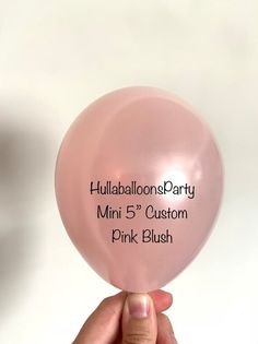 a person holding up a pink balloon with the name of their party printed on it