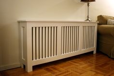 a white radiator sitting on top of a wooden floor next to a couch