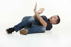 a man sitting on the floor with his hands up in the air and looking up