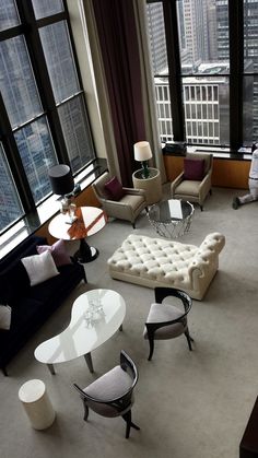 a living room filled with lots of furniture and large windows overlooking the cityscape