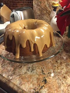 a bundt cake sitting on top of a glass plate covered in icing and drizzle