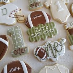 decorated cookies are arranged on a table for a baby's first - to - be football party