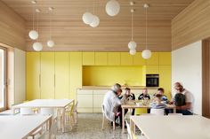 people sitting around a table in a yellow and white kitchen