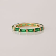 a gold and green ring on a white surface