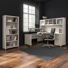 an office with black walls and wooden floors, white desks and bookcases