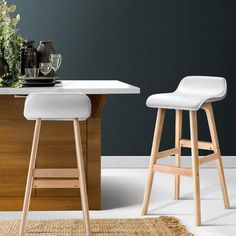 two white stools sitting in front of a table with flowers and glasses on it